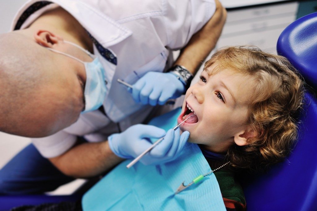 Dentist checking young boy's teeth