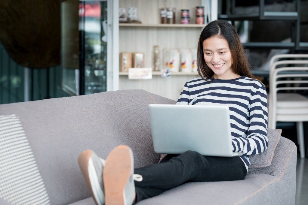 Woman sitting on couch while using laptop