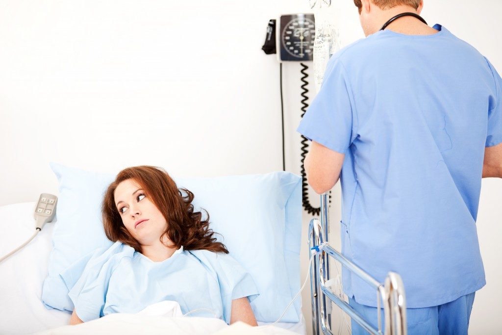 Female patient on hospital bed while the nurse checks on her
