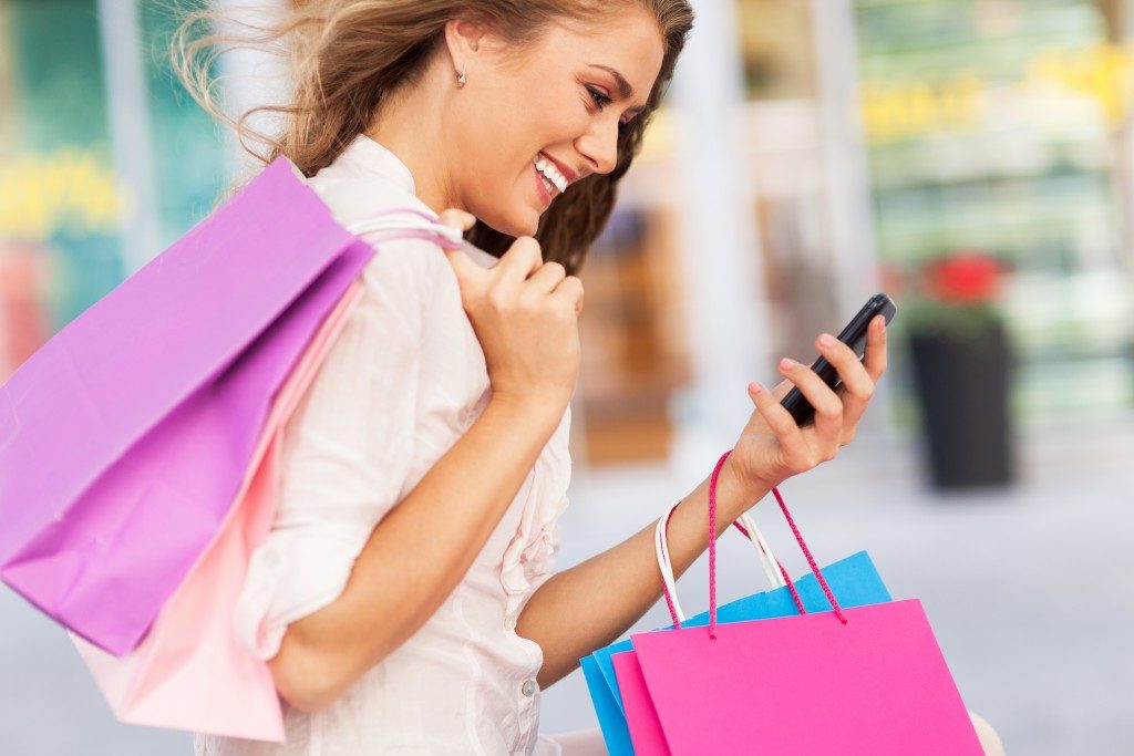 woman looking at her phone and holding shopping bags