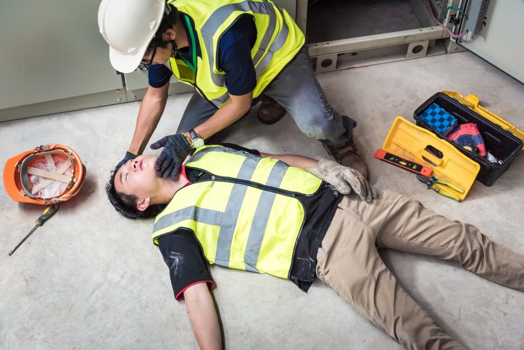 man checking his injured colleague's condition