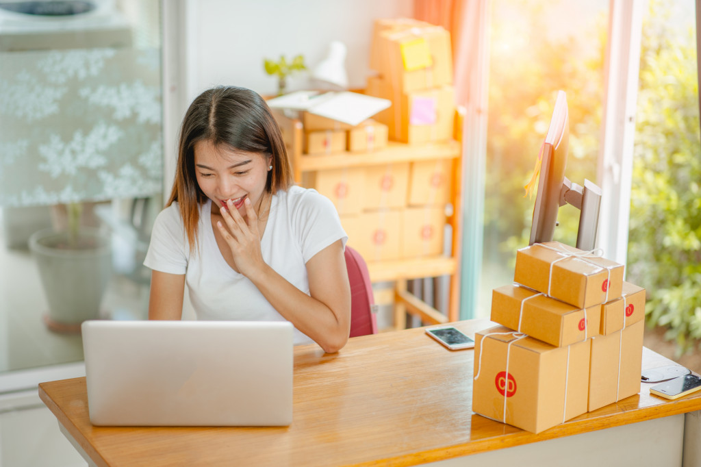 business owner about to send packages while looking at her laptop