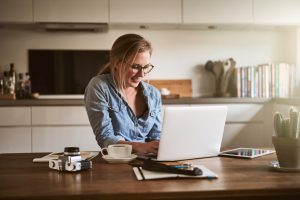 Woman working on her laptop from her home kitchen