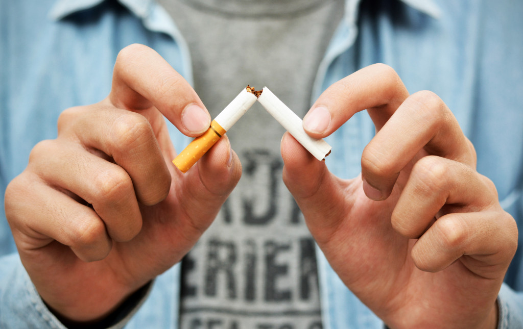 stop smoking concept shown through a man breaking cigarette in half