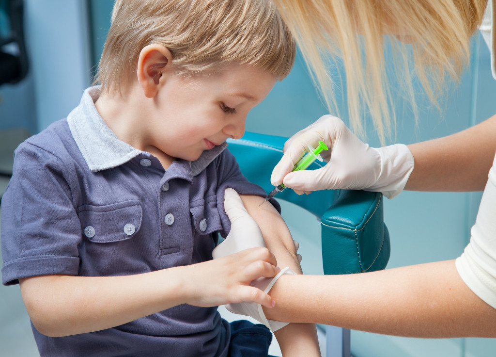 smiling little boy while getting his vaccine from a female healthcare provider