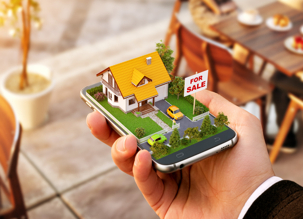 A hand holding a phone with a 3d real estate model for sale