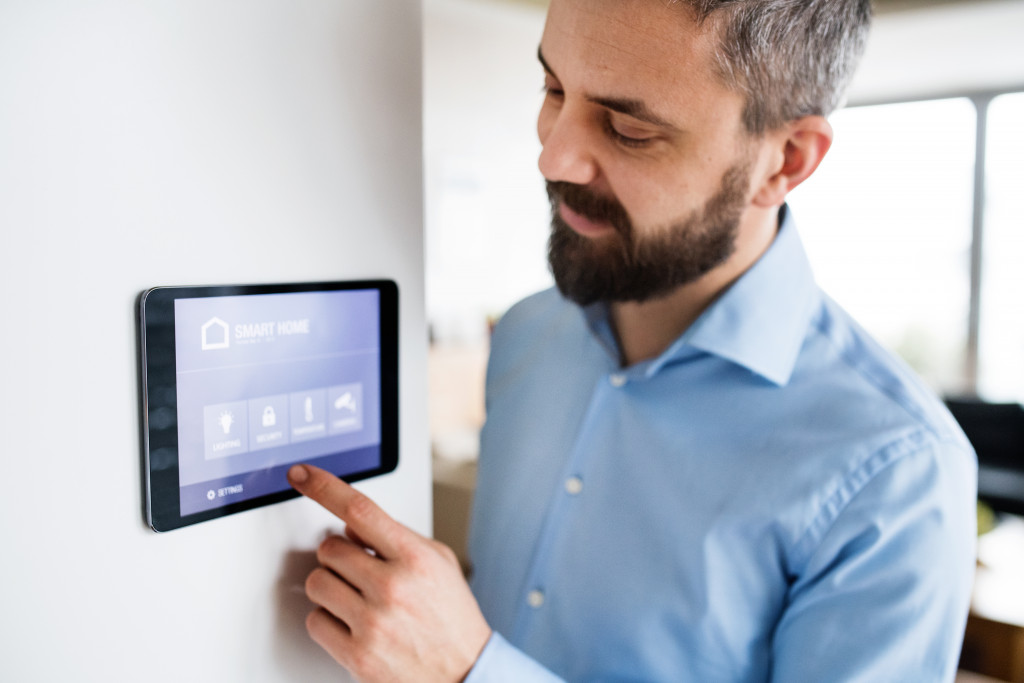 A man adjusting the temperature via a thermostat